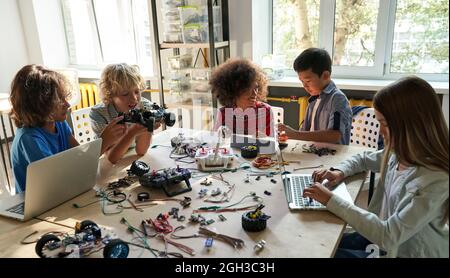 Diverse school children students group building robotic cars using computers. Stock Photo