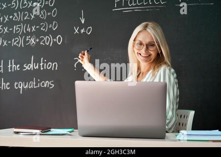 Female school college teacher having online distance virtual class in classroom. Stock Photo