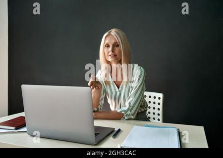 Female school college teacher teaching online remote virtual class in classroom. Stock Photo