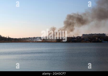 Fire in the nature. The reeds are burning near the village. Fire in the heat. Stock Photo