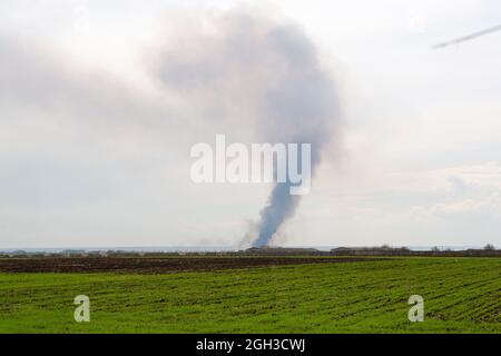 Fire in the nature. The reeds are burning near the village. Fire in the heat. Stock Photo