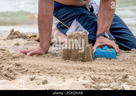 Dad shows kids how to make a perfect sand castle, as he plays on the beach in Michigan USA Stock Photo