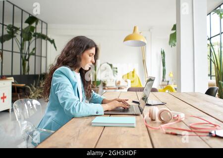 Close up of beautiful young business woman typing on laptop keyboard. Female office worker in formal suit works concentrated on work in modern office Stock Photo