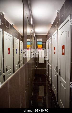 Hall with many doors. Narrow hall with a lot of mirrors and doors, walls and floors are finished with tiles Stock Photo