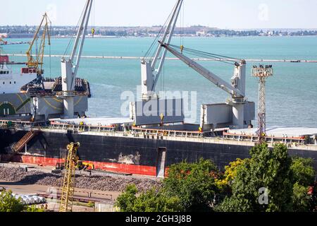 Vessel dry cargo on loading by iron ore, unloading in port. Bulker in port. Stock Photo