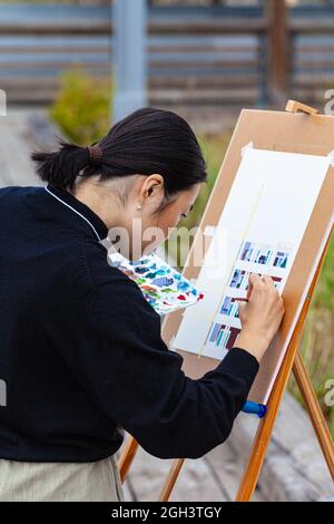 Young Asian female artist painting on canvas doing art projects on her ...