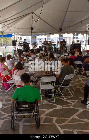 Greek band plays at the Long Beach Greek Festival in front of a crowd featuring a man in a wheelchair Stock Photo