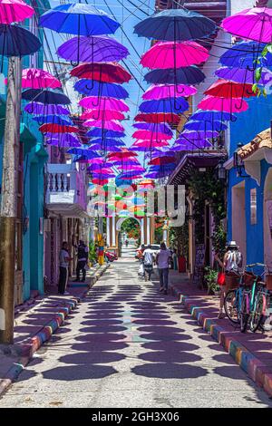 Hanging colourful umbrellas which provide shade along Calle de la Magdalena, Barrio Getsemani, Cartagena, Colombia. Stock Photo