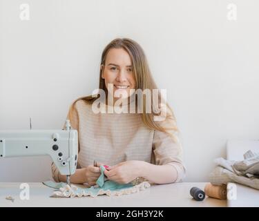 Happy female atelier owner working at workplace with sewing machine Stock Photo