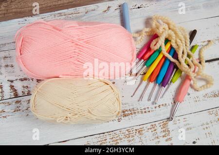 Pastel color yarns for crocheting and hooks on a wooden background Stock Photo