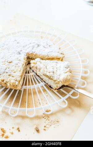 round apple crumble with icing sugar, served on a white cake grid Stock Photo