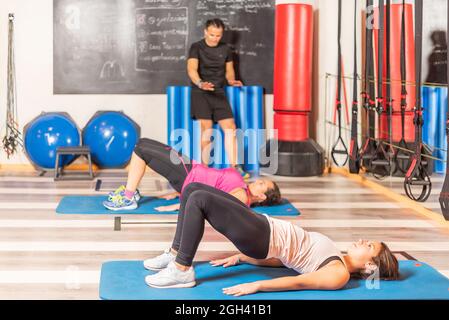 Women doing pelvic exercise with trainer in gym Stock Photo