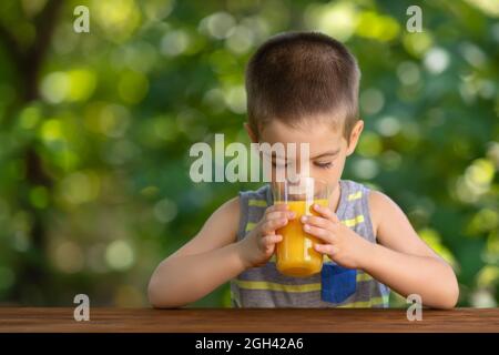 little boy drinking orange juice from glass Stock Photo