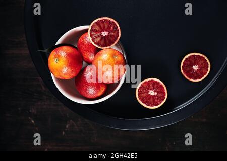 Red blood oranges in a bowl on a dark background. Stock Photo