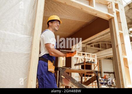 Joyful male builder using laptop at construction site Stock Photo