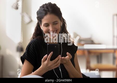 Happy Latin woman in earphones talking on cellphone Stock Photo