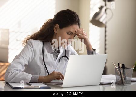 Tired frustrated female doctor feeling stress at workplace Stock Photo