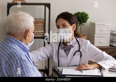 GP doctor in face mask giving support and consultation Stock Photo