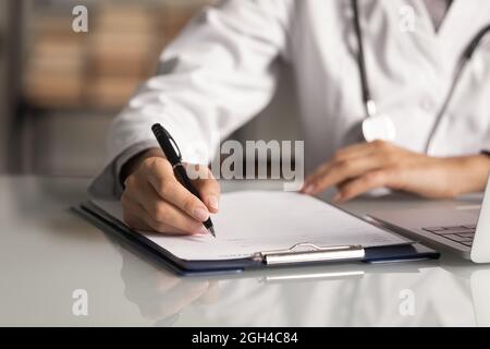 Hands of general practitioner filling paper medical records Stock Photo