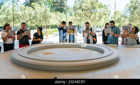 Cupertino, CA, USA - August 2019: Apple Store Cupertino with people looking at Infinite Loop Apple Headquarters through virtual reality using iPad tab Stock Photo