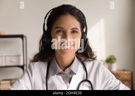 Happy general practitioner in headphones giving online help Stock Photo