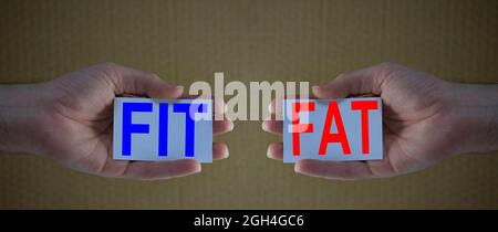 Fit and Fat creative concept: man hands holding cards with the words FIT and FAT.  Concept of healthy lifestyle, fitness, sport, nutrition and body po Stock Photo