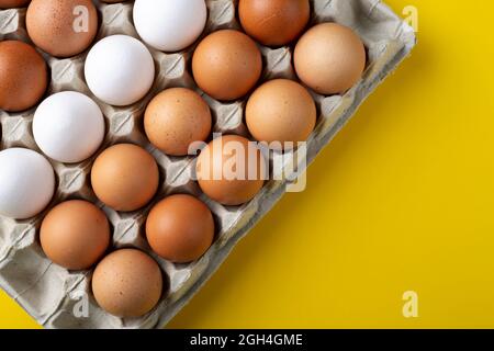 Nice big rural fresh eggs in cardboard egg box holder with colorful yellow background. Space for text. Stock Photo