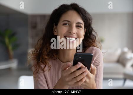 Portrait of laughing happy young hispanic woman holding cellphone. Stock Photo