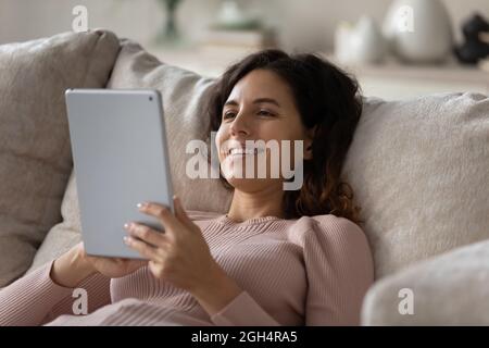 Relaxed happy young woman using digital computer tablet. Stock Photo