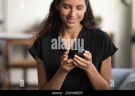 Happy smartphone user sitting on couch with gadget Stock Photo