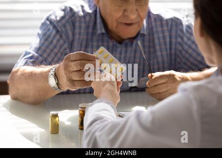 Female GP doctor giving pills to older patient at appointment Stock Photo