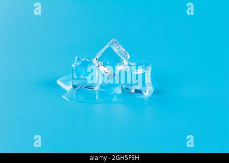 Melting three ice cubes on a blue background, meltwater from melting ice. Stock Photo