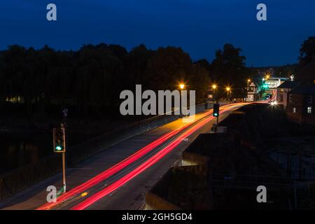 Traffic trails seen over the Old Dee Bridge in Chester at twilight in September 2021. Stock Photo