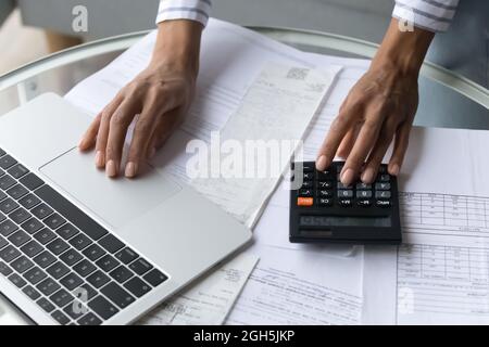 Black female hands using calculator and laptop at home office Stock Photo