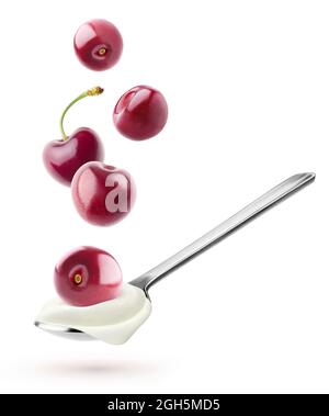 Isolated yogurt with fruits. Spoon with natural yogurt and cherries flying over it isolated on white background Stock Photo