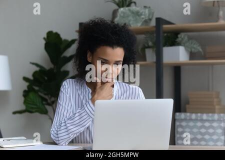 Pensive black business lady read analytic report from laptop screen Stock Photo