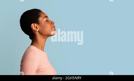 Profile Of Young African-American Woman Standing With Closed Eyes Over Blue Background Stock Photo