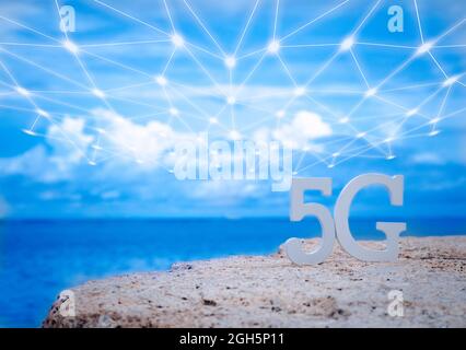 Symbol of white 5G with wifi and transmission network on stone seaside with blue sky. Network internet, communication wireless and 5G standard of sign Stock Photo