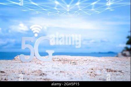 Symbol of white 5G with wifi and transmission network on stone seaside with blue sky. Network internet, communication wireless and 5G standard of sign Stock Photo