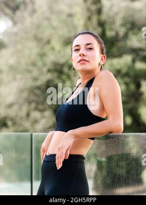 High angle of exhausted middle aged Hispanic female freelancer rubbing eyes while sitting on bed and working remotely on laptop at home Stock Photo