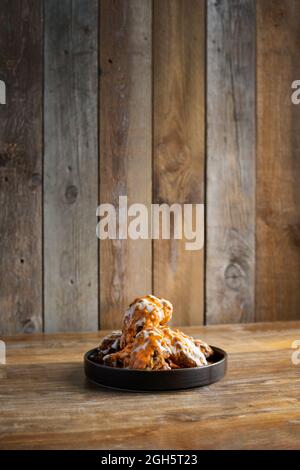 Hot tasty buffalo chicken wings with sauces placed on round shaped plate on wooden table Stock Photo