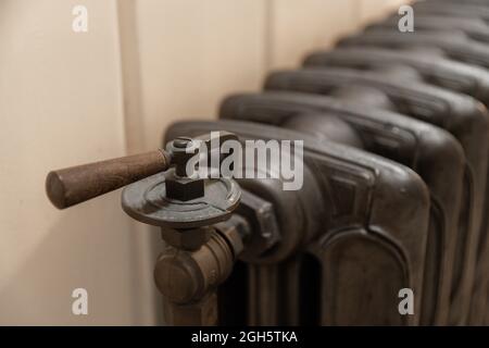Rusty metal valve of old radiator for temperature regulation in room at home Stock Photo
