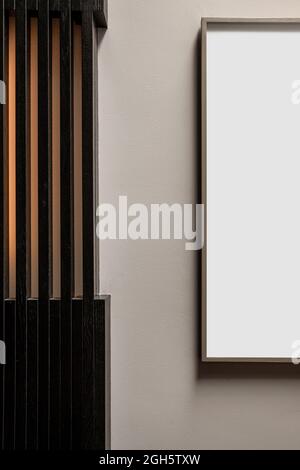 Fragment of interior design with white mockup rectangular frame hanging on wall near striped pillar Stock Photo