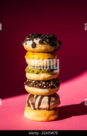 Tower of donuts of different colors and flavors on pink background Stock Photo