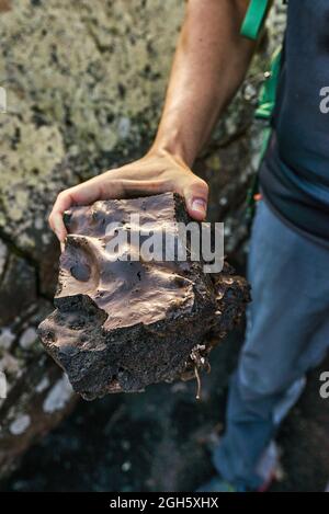 From above anonymous man demonstrating piece of rough rock while exploring countryside in summer Stock Photo