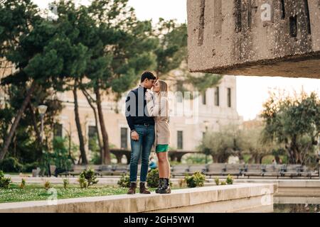 Young stylish couple standing close to each other in city street Stock Photo