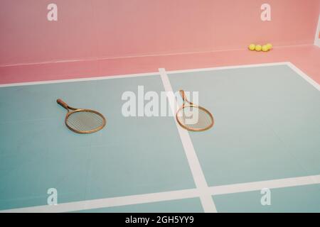 Creative design of tennis rackets against small balls on sports ground with marking lines
