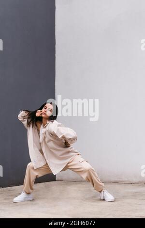Through glass of thoughtful female standing near window and observing street while looking away Stock Photo
