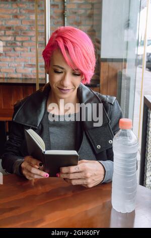 From above of crop female in casual clothes holding opened notebook on wooden table Stock Photo