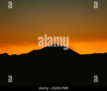 Breathtaking landscape of silhouette of mountain range on background of bright orange sundown sky Stock Photo